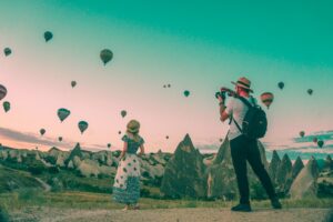 Man taking photo of a woman with hot air balloons - Travel Prizes