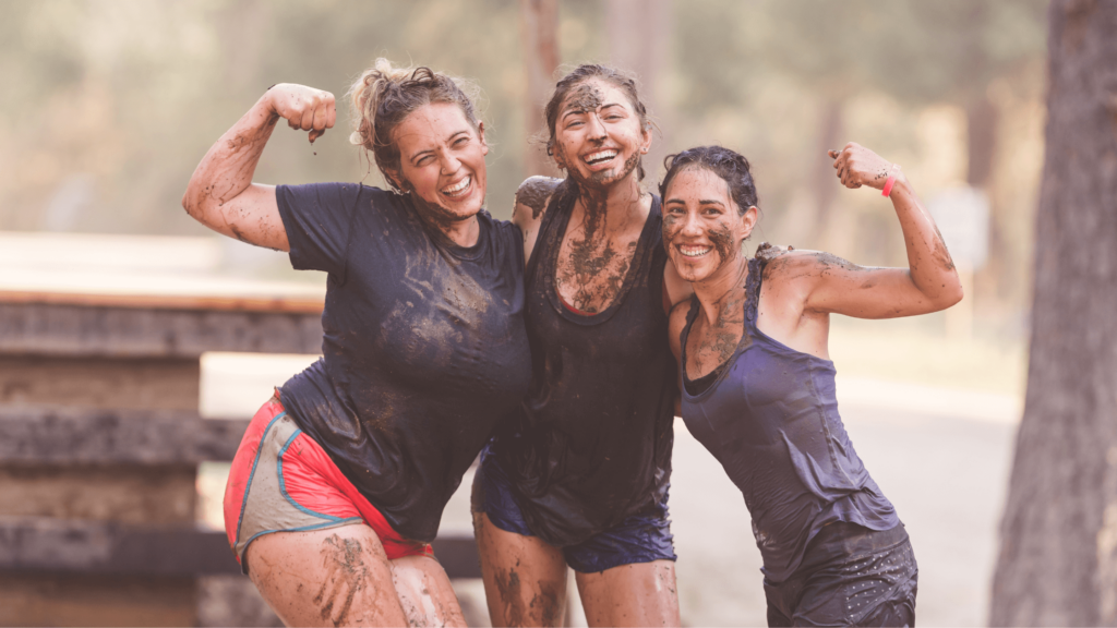 charity fundraiser three women in shorts and shorts covered in mud