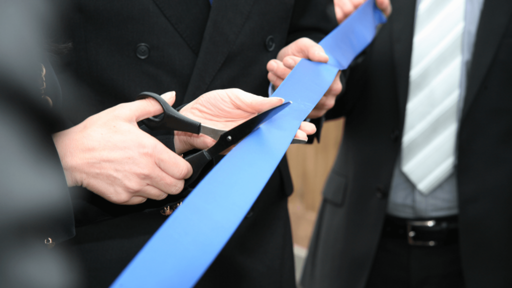product launch or a new opening cutting a blue ribbon with scissors